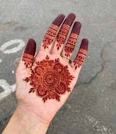 a hand with henna on it that is showing the intricate pattern and design in red