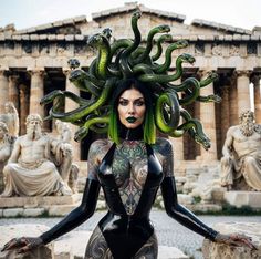 a woman with green hair and tattoos is standing in front of statues wearing snakes on her head