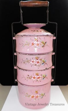 a pink metal container with flowers painted on it