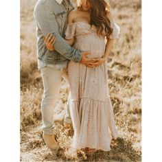 a pregnant woman standing next to a man in a field