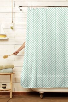 a person holding a brush in front of a shower curtain that has an arrow pattern on it