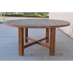 a wooden table sitting on top of a cement floor next to a wall and sidewalk