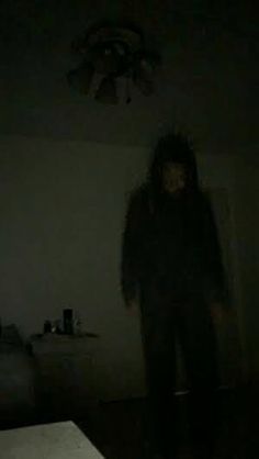 a person standing in a dark room next to a bed