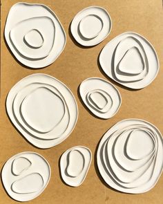 six white plates sitting on top of a cardboard box with circles cut out of them