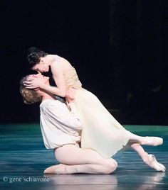 a man and woman are kissing on the floor in front of a black stage backdrop