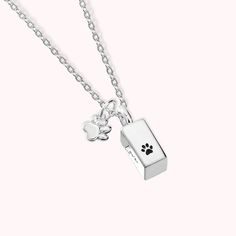 a dog's paw print is on the back of a silver necklace with a small box charm