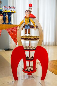 there is a toy man sitting on top of a stand with cupcakes in front of him