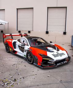 an orange and white race car parked in front of a building