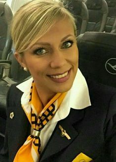 a woman with blonde hair wearing an orange and black neck tie on an airplane seat