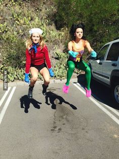 two women dressed in costumes are running down the road with their hands on their hipss