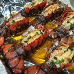 cooked lobsters on tin foil with lemon wedges and parmesan cheese sauce