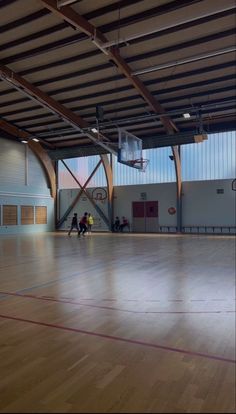 two people are playing basketball in an indoor gym with hard wood floors and high ceilings