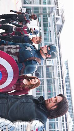 several people dressed as captain america standing in front of a tall building