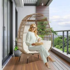 a woman is sitting in a hanging chair on the porch with her legs crossed and looking at the camera