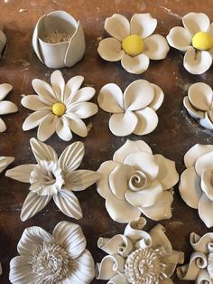 many white flowers are sitting on the table next to cups and spoons with yellow centers