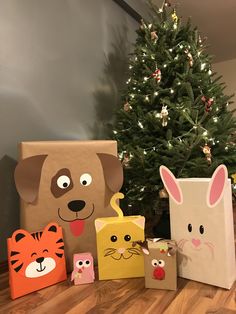 several paper bags with animals on them sitting in front of a christmas tree and a small toy cat