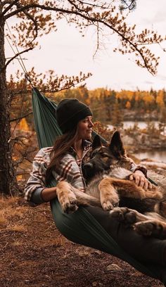 a woman sitting in a hammock with her dog