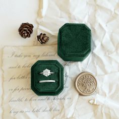 two rings sitting on top of a piece of paper next to a wax seal and pine cone