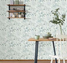 a dining room table with two chairs and a vase on it next to a wallpaper