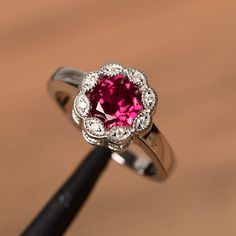 a close up of a ring with a pink stone in the center and white diamonds around it