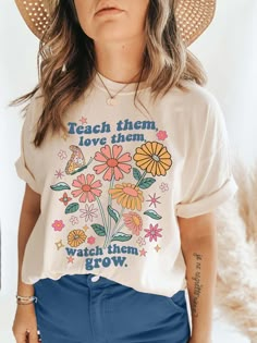 "Retro groovy 1970s flowers and butterfly t-shirt that says Teach them, love them, watch them grow. Perfect for any teacher or teaching student -- makes a great co-worker gift or graduation gift! The t-shirt is soft and cozy made with UNISEX sizing to be inclusive for everyone. C O L O R ▸ Natural F I T + S I Z I N G ▸ UNISEX sizing ▸ Please check the size chart in the photo section before ordering ▸ Model has sized up for an oversized fit ▸ T-shirt may be knotted or have the sleeves rolled up i Retro School Shirts, Groovy Teacher Shirt, Retro Teacher Shirts, Cute Preschool Teacher Outfits, Cute Elementary Teacher Outfits, Back To School Fits 2023, Teacher Graphic Tees, Retro T Shirt Designs, Teacher Clothes Teaching Outfits