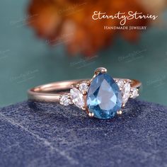 an emerald and diamond three stone ring on top of a blue rock with flowers in the background