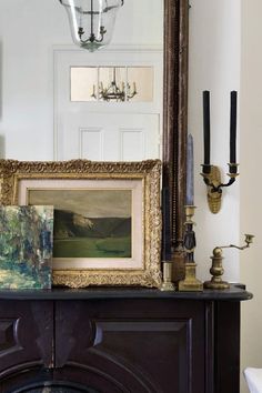 a painting is sitting on top of a mantle in front of a mirror and candles