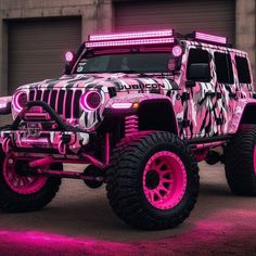 a pink jeep is parked in front of a building with its lights on and it's hood up