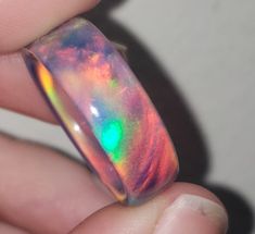 OPAREX synthetic opal is more durable and cost effective than your average opal, ensuring you will have your ring for years to come! The color shifts depending on the angle it is viewed, creating a rainbow of colors. The material is semi transparent, giving it an almost glowing effect. It is inspired by Dragon's Fire, displaying all the colors of a flame at it's hottest point. 8 mm wide This synthetic opal ring comes in a size 8 1/2 and was turned on a lathe. It is then sanded from 60 grit all t Unique Iridescent Round Opal Ring, Iridescent Opal Ring With Unique Style, Unique Handmade Iridescent Opal Ring, Multicolor Opal Round Ring, Handmade Iridescent Opal Ring, Multicolor Opal Gemstone Ring, Multicolor Opal Ring Gift, Iridescent Opal Ring As A Gift, Iridescent Opal Ring Gift