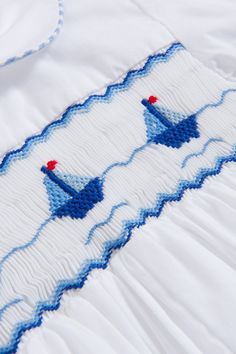 a white and blue quilted bed spread with two boats on it's side