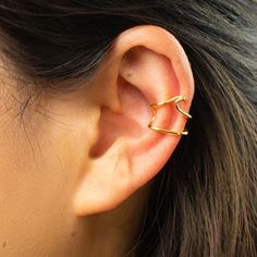 a woman's ear is shown with two small gold rings