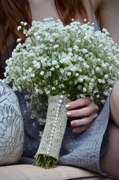 a woman holding a bouquet of white flowers in her hands and sitting on a couch