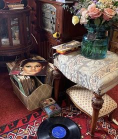 an old record player sitting on top of a table next to a vase filled with flowers