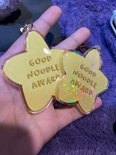 two gold heart shaped keychains with words on them that say, good noodlele