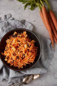 a bowl filled with shredded carrots and raisins on top of a cloth