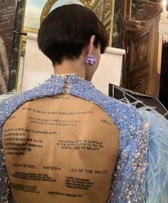 the back of a mannequin's dress with words written on it, in front of a mirror