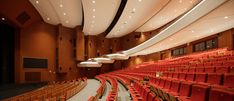 an empty auditorium with red seats and lights