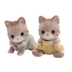 two small stuffed animals sitting next to each other on a white surface with one cat wearing a sweater