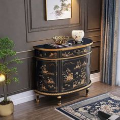 a black and gold decorated cabinet in a living room next to a potted plant