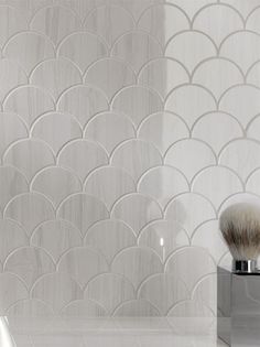 a shaving brush sitting on top of a stand next to a white tiled wall