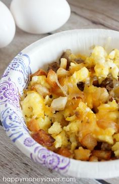 an egg casserole in a paper bowl on a wooden table next to eggs