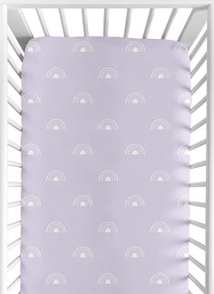 a baby crib bed with a purple and white rainbow print on the sheeting