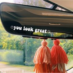 two tasselled pom poms hanging from the rearview mirror