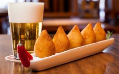 some food is on a plate next to a glass of beer and a red pepper