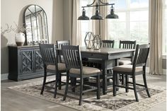 a dining room table and chairs in front of a window with an area rug on the floor