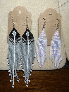 three pairs of beaded earrings on display in front of a price tag for each pair