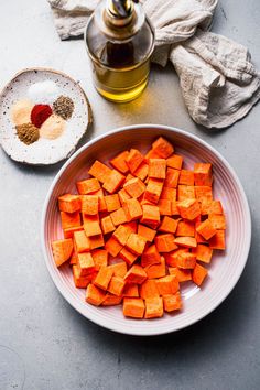 chopped up carrots in a white bowl next to a tea pot and salt shaker