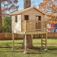 a wooden tree house in the middle of a yard