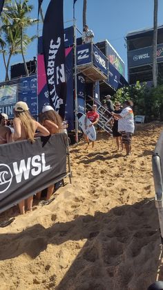 some people are sitting in chairs on the beach and one person is holding a surfboard