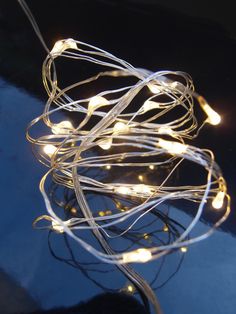 a string of lights is hanging from a wire on a table with a blue background